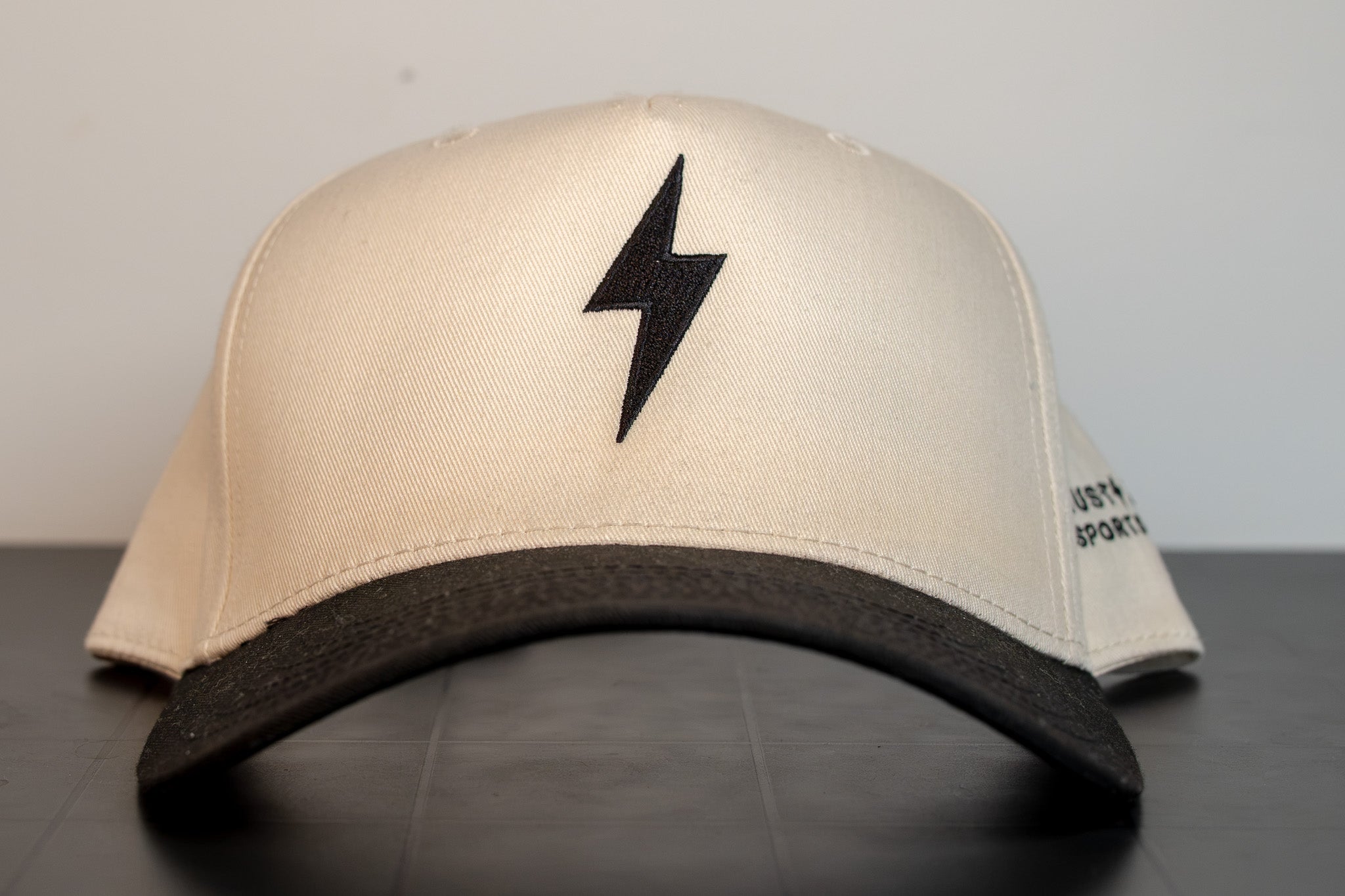 cream cap with black brim and a single black lightning bolt embroidered on the front