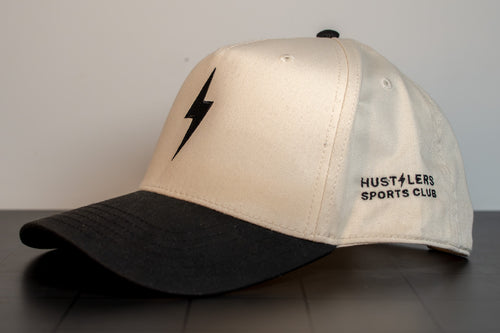 side view of the cream and black bolt cap with hustlers sports club embroidered on the panel