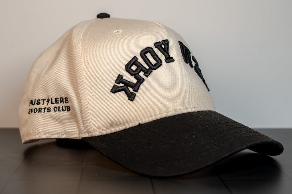 alt: side view of the new york cap with hustlers sports club embroidered on the panel