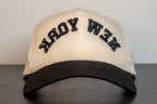 alt: cream cap with black brim and new york arched across the front in black embroidery