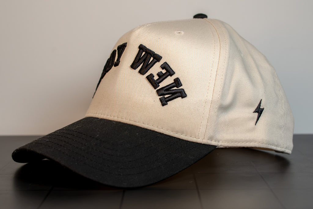 alt: angled view of the cream and black new york cap showing the bolt mark on the side panel
