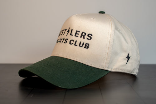 cream cap with forest green brim, hustlers sports club block wordmark and hsc signature on the side panel