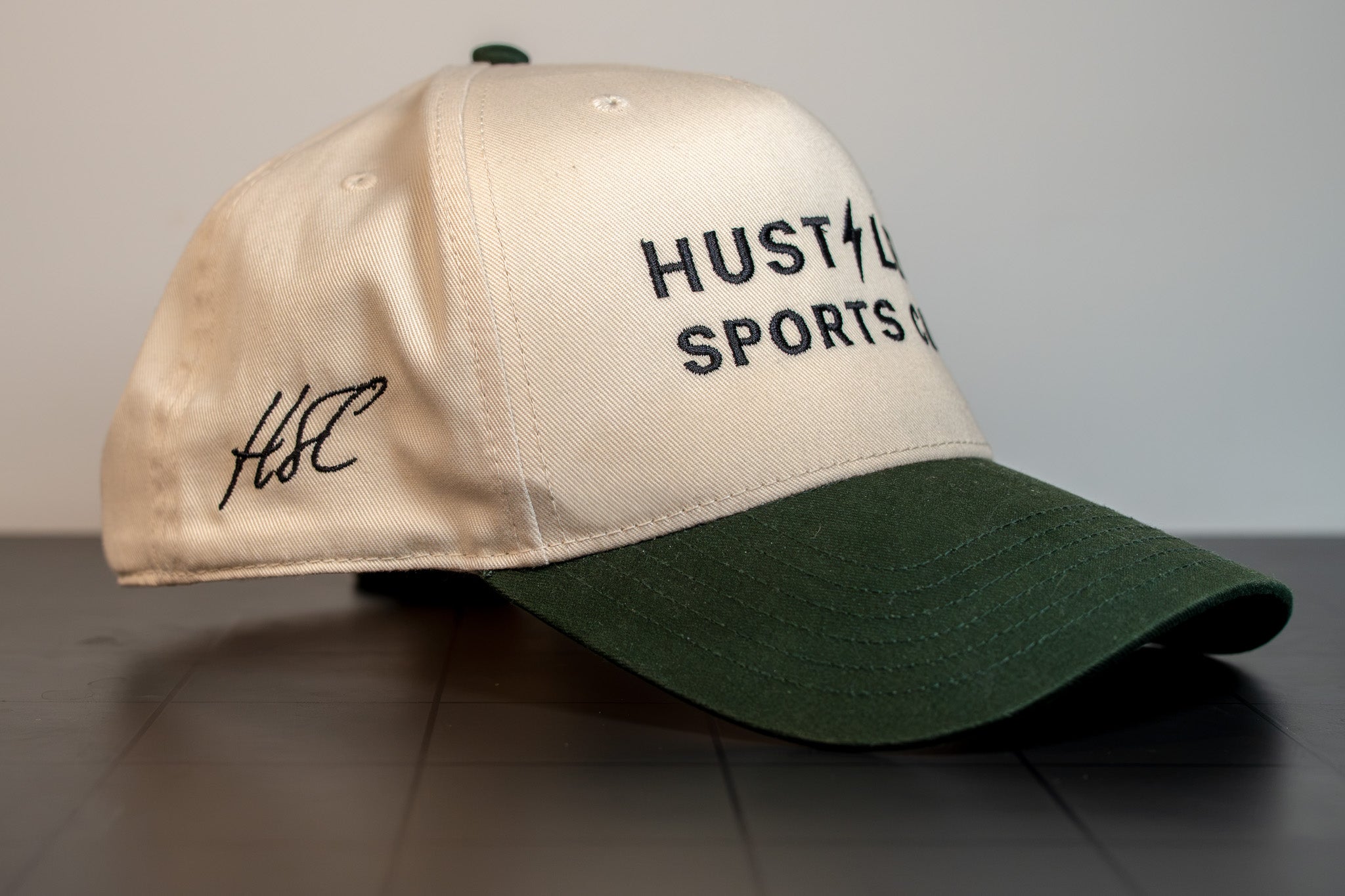 side view of the cream and green hustlers sports club cap showing the bolt mark and structured crown